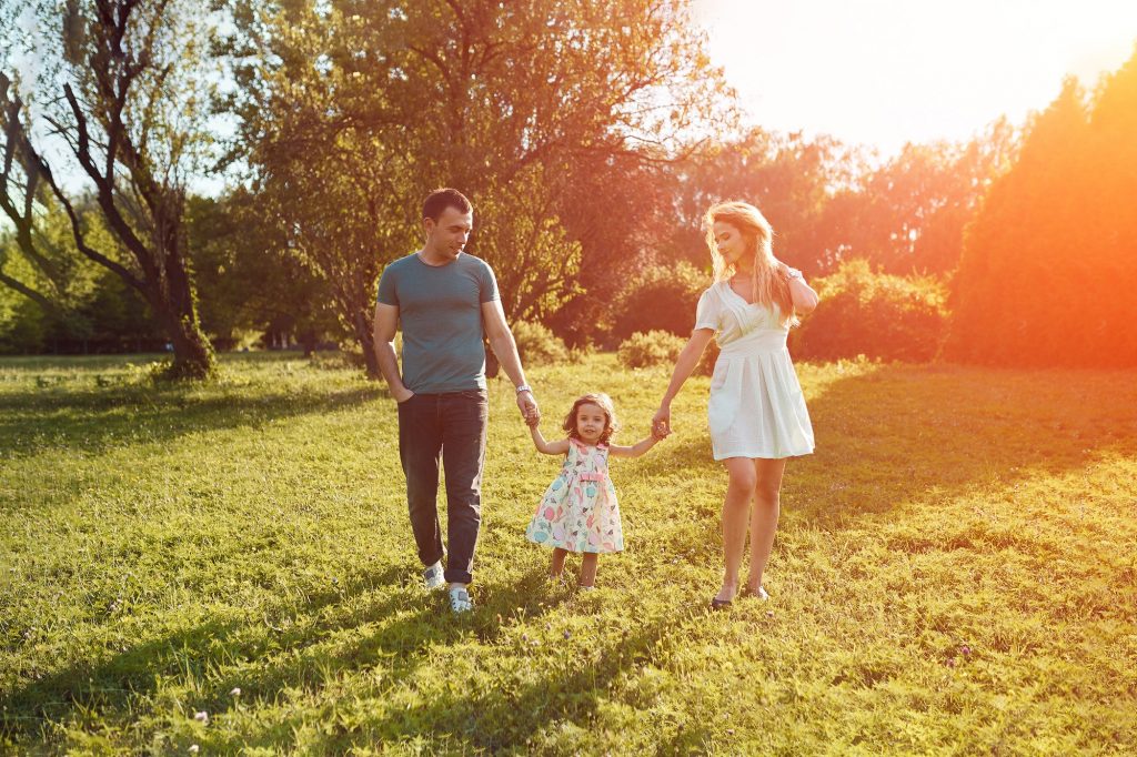 Happy young family spending time together outside in green nature.